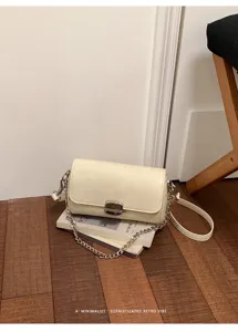 Dettaglio della borsa a tracolla bianca minimalista con catena elegante e chiusura chic.