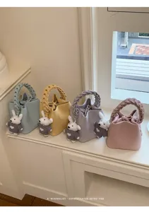 Minimalistische Retro-Eimer Tasche mit geflochtenem Griff und süßem Hasen-Anhänger.