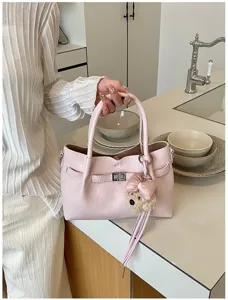 Bolso de mano de cuero rosa, vista detallada con cierre metálico y lindo oso colgante.