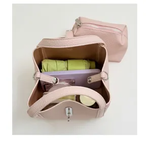Elegante bolso de mano tipo cubo en cuero rosa con cierre metalico y comoda bandolera.