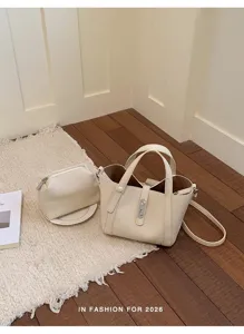 Vista detallada del elegante bolso tipo cubo beige con estuche a juego sobre una alfombra.