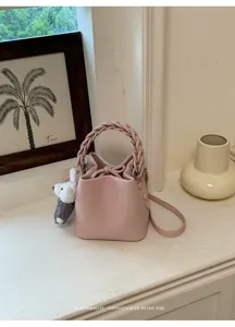 Rosa Leder Beuteltasche mit geflochtenem Griff und süßem Bärenanhänger, schicke Umhängetasche.