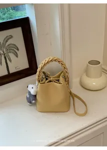 Gelbe Leder Eimer Tasche Detailansicht mit geflochtenem Griff und Hundemotiv fuer den Alltag.