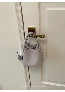 Schicke Damen Leder Eimer Tasche mit geflochtenem Griff und süßem Plüsch Anhänger für Alltag.