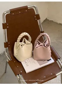 Detailansicht schicker Eimerentaschen mit geflochtenem Griff in Beige und Rosa auf Stuhl.