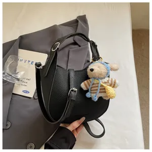 Vue détaillée du sac à main en cuir noir avec breloque ours en tricot mignon et boucle en métal.