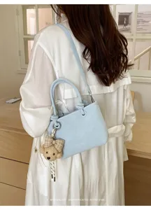 Detailansicht einer hellblauen Beuteltasche mit süßem Bärenanhänger im schicken Retro-Stil.