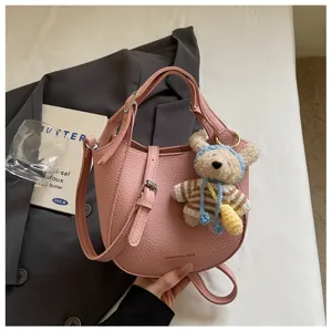 Sac seau bandoulière en cuir rose avec pendentif ours, élégant sac à main pour femme.