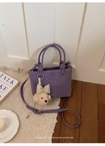 Detailansicht der violetten PU-Leder-Eimer Tasche mit süßem Welpen-Anhänger und Henkel.
