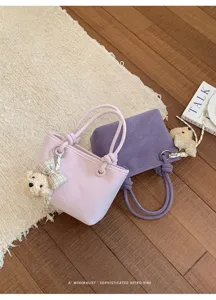 Schicke minimalistische Eimertasche mit Bärenanhänger und geflochtenem Griff für den Sommer.