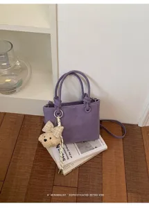 Detailansicht der stylischen violetten Leder-Eimer-Tasche mit Bären-Anhänger und Deko.
