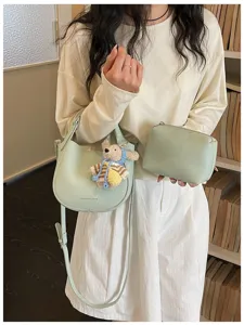 Sac bandoulière minimaliste en cuir vert clair vue détaillée avec charm ours et pochette.