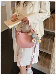 Vue détaillée du sac seau élégant et tendance en cuir rose avec un joli pendentif ours.