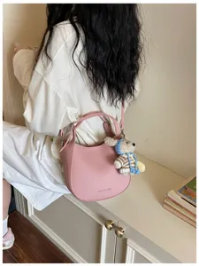 Détail de sac seau rose, élégant sac à bandoulière en cuir avec charmant pendentif.