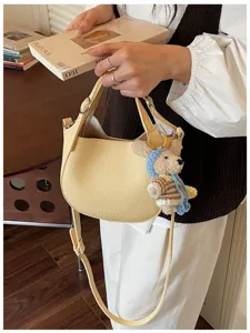 Sac à bandoulière chic en cuir jaune avec charm ours, sac hobo élégant pour femmes.