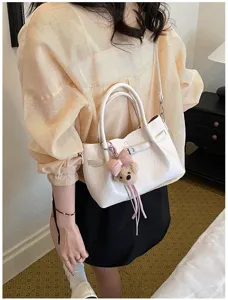 Vista detallada de un elegante bolso blanco con un lindo lazo rosa y un encantador osito.