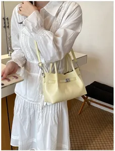 Primer plano de un elegante bolso de mano amarillo claro con cierre de metal elegante.