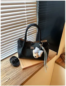 Vista detallada del bolso tote negro con cierre metálico, correa y bonito dije de oso.