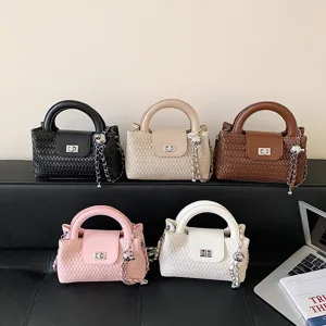 Detail view of woven top handle crossbody bag displaying multiple color options and metal chain.