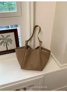 Gros plan détaillé sur le sac cabas minimaliste en cuir kaki avec une texture rétro.