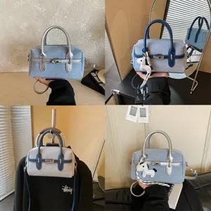 Detailed view of fashionable denim contrast color handbag with metallic lock and shoulder strap.