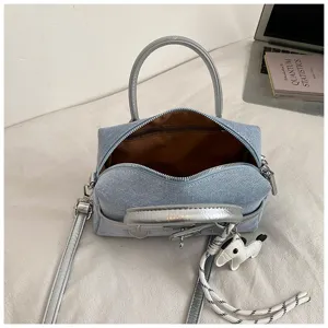 Detailed view of the stylish denim pillow bag with silver handles, metal lock, and cute dog charm.