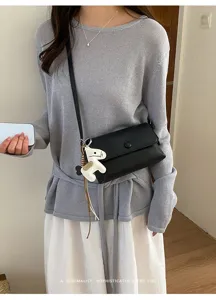 Borsa a tracolla quadrata nera minimalista con grazioso ciondolo cavallo bianco, dettaglio.