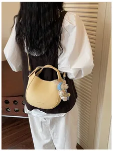 Vue détaillée du sac seau jaune élégant avec charmant pendentif d'ours et texture en cuir fin.