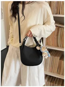Gros plan d'un sac bandoulière en cuir noir avec porte-clés ours mignon et stylé.