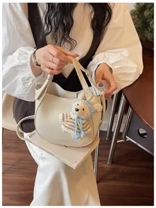 Vue détaillée du sac seau tendance en cuir beige avec charmant petit ours en peluche tricoté.