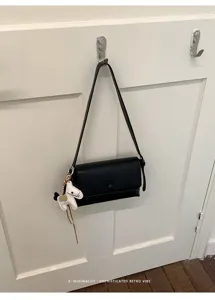 Borsa a spalla nera minimalista sotto l'ascella con grazioso ciondolo cavallo bianco quotidiano.