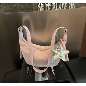 Detalle de un bolso hobo rosa con un brillante colgante de estrella plateada y correas.