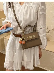 Braune Mini Kelly Umhängetasche Detail, mit strukturiertem Leder und Kirschenanhänger.