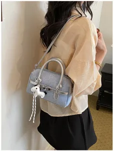 Detailed view of the stylish contrast color shoulder pillow bag with silver handles and cute charm.