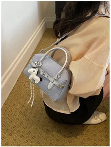 Detailed view of the stylish contrast color shoulder pillow bag with silver handles and charm.