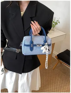 Stylish denim colorblock handbag with charming dog pendant, perfect for daily summer commuting.