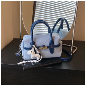 Blue denim colorblock handbag with top handle, turn-lock closure and cute horse charm.