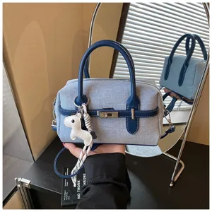 Blue denim pillow handbag detail, chic color contrast design with metal lock and charm.