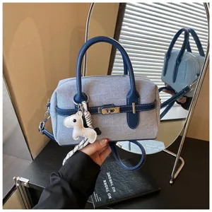 Close-up detail of the stylish blue denim contrast handbag featuring a cute horse charm and lock.