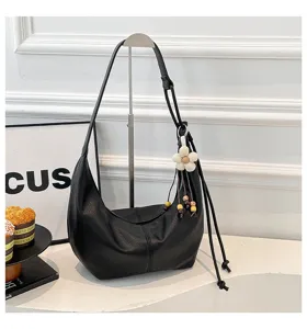 Detailaufnahme einer stylischen schwarzen Leder Schultertasche mit blumigen Perlenanhänger.