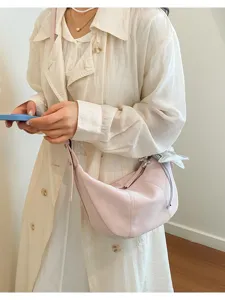 Primer plano de un bolso cruzado rosa elegante con un colgante de estrella plateada.