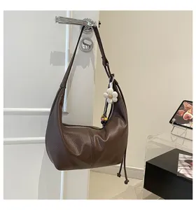 Detailaufnahme der stilvollen braunen Leder-Achseltasche im Knödel-Design mit Blumenanhänger.