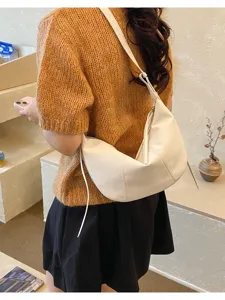 Vista detallada del bolso cruzado blanco con diseño curvo elegante y cierre de cremallera.
