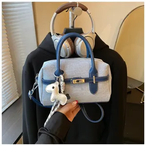 Stylish denim color-block shoulder bag with cute horse charm detail, perfect for daily commute.