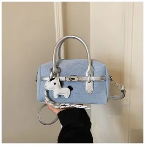 Chic denim top handle bag with silver trim, metal lock, and cute horse charm detail.