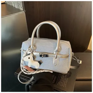 Detail view of stylish denim patchwork pillow bag with silver handles and cute horse charm.