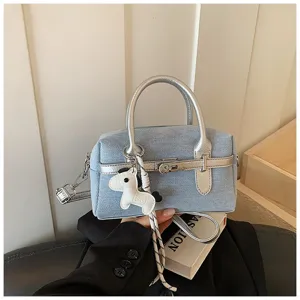 Stylish denim bowling bag with silver handles, crossbody strap, and cute horse charm for women.