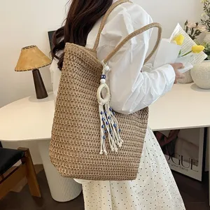 Detailansicht der gewebten Stroh-Tragetasche für Damen mit elegantem Quasten-Anhänger.