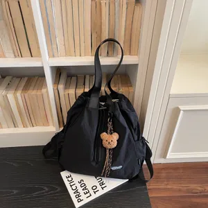 Detail view of the black multi-functional drawstring bucket bag with cute bear pendant.