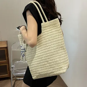 Detailaufnahme einer stylischen Strohgewebten Tasche mit Textur, Riemen und schickem Dekorelement.